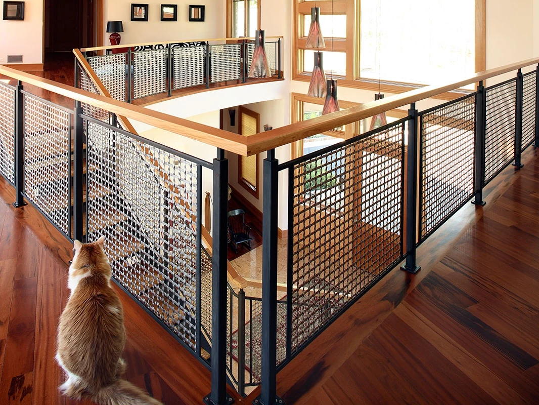 Framed woven metal mesh infill beneath timber handrails around an interior atrium
