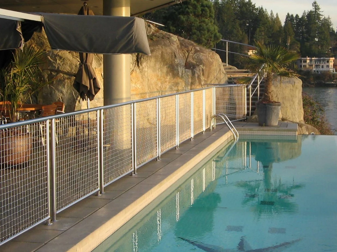Metal mesh infill panels along an outdoor terrace beside a swimming pool