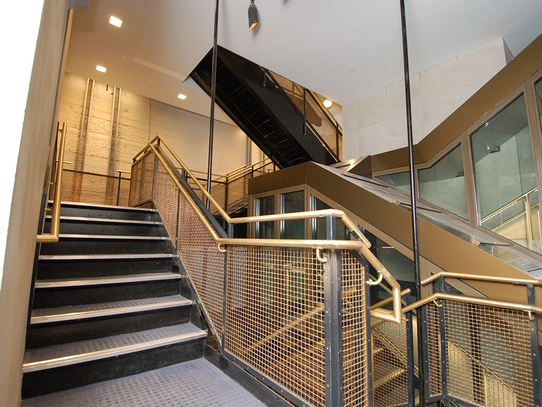 Framed woven metal mesh infill along interior stair railings