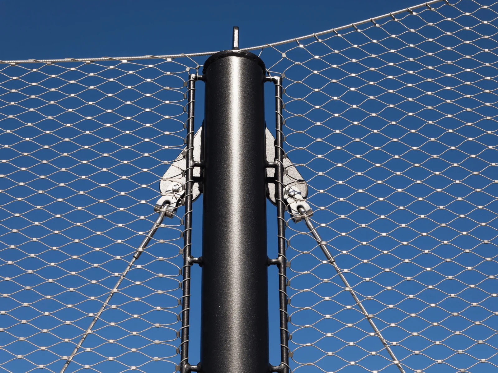 Rope mesh and perimeter cables attached to a metal post through visible connection fittings