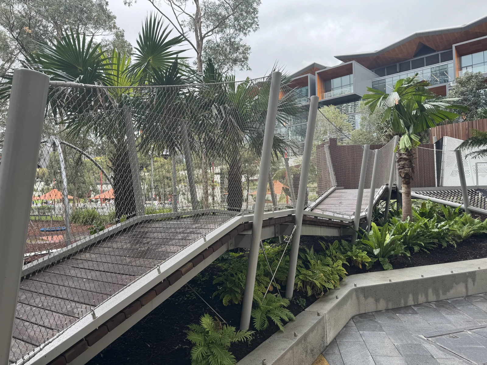 Rope mesh infill along a footbridge beside a landscaped garden