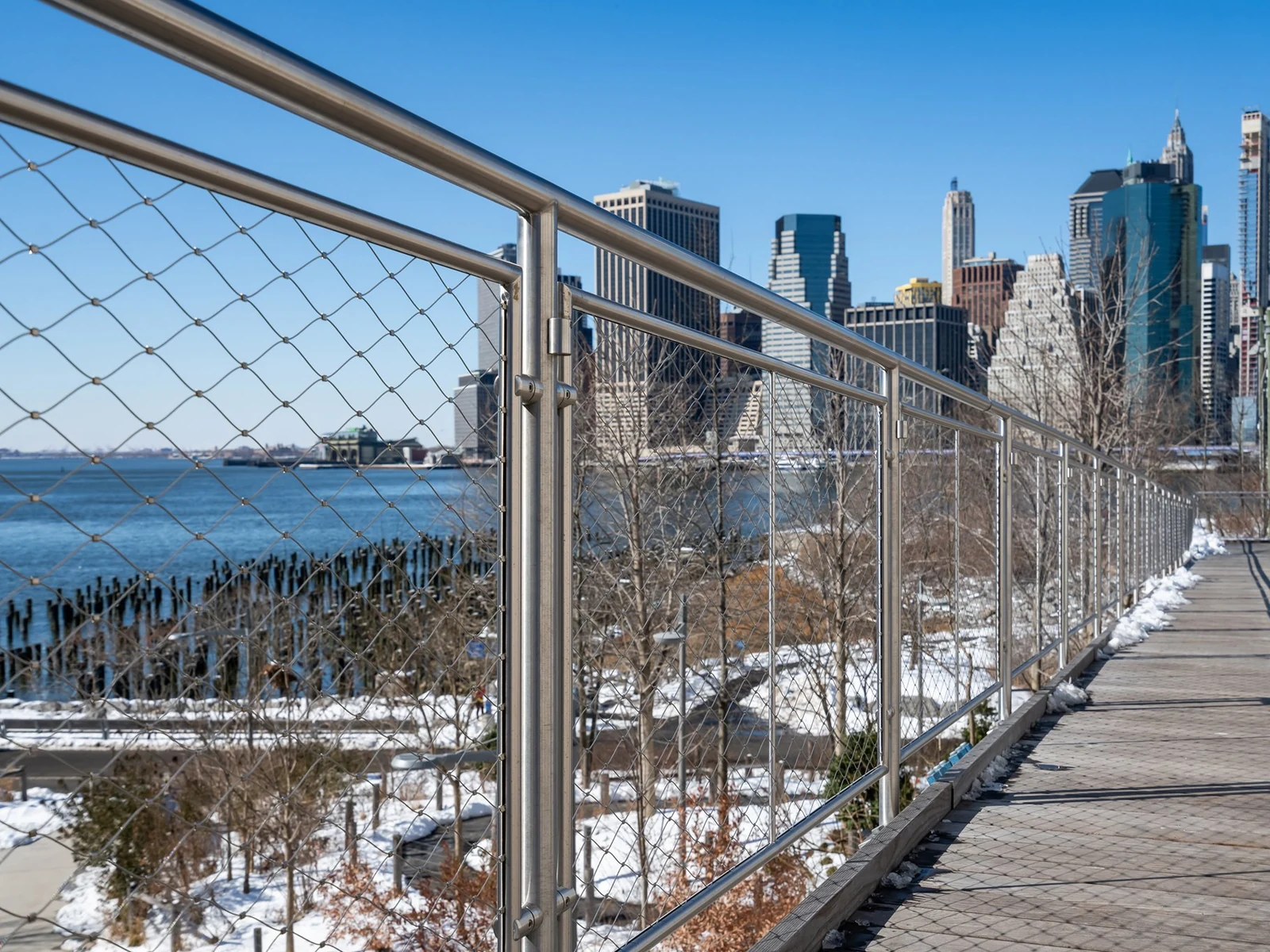 Rope mesh panels beneath a handrail along a waterfront walkway
