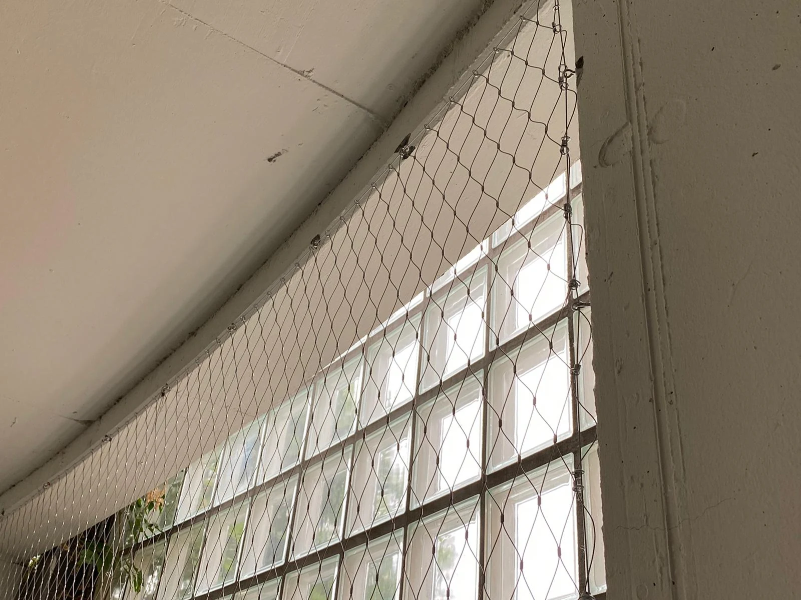 Rope mesh spanning a window opening with attachments around the frame
