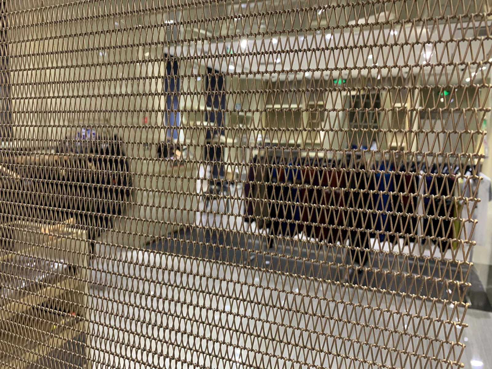 Repeated spiral wire loops in a commercial interior screen with seating behind