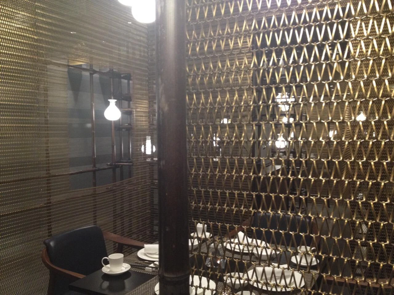 Spiral metal mesh panels separating restaurant dining tables