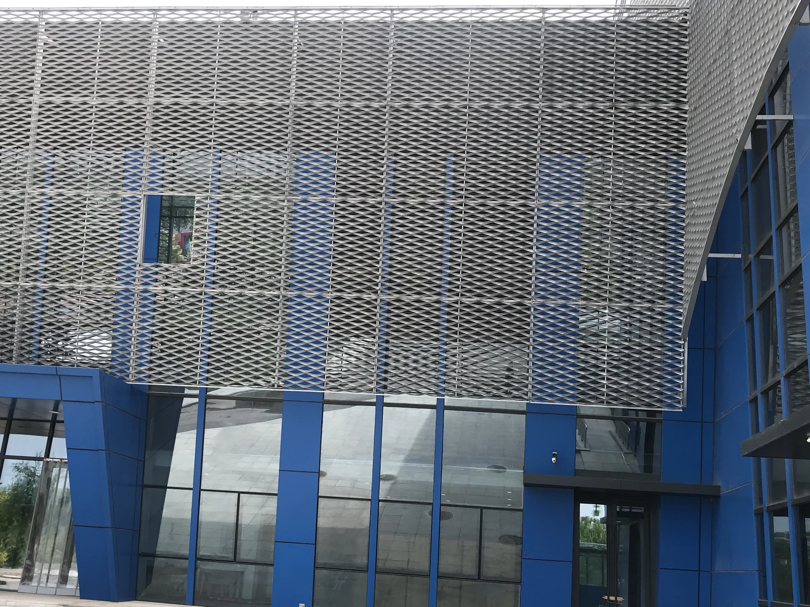 Expanded metal panels above and beside a glazed building entrance