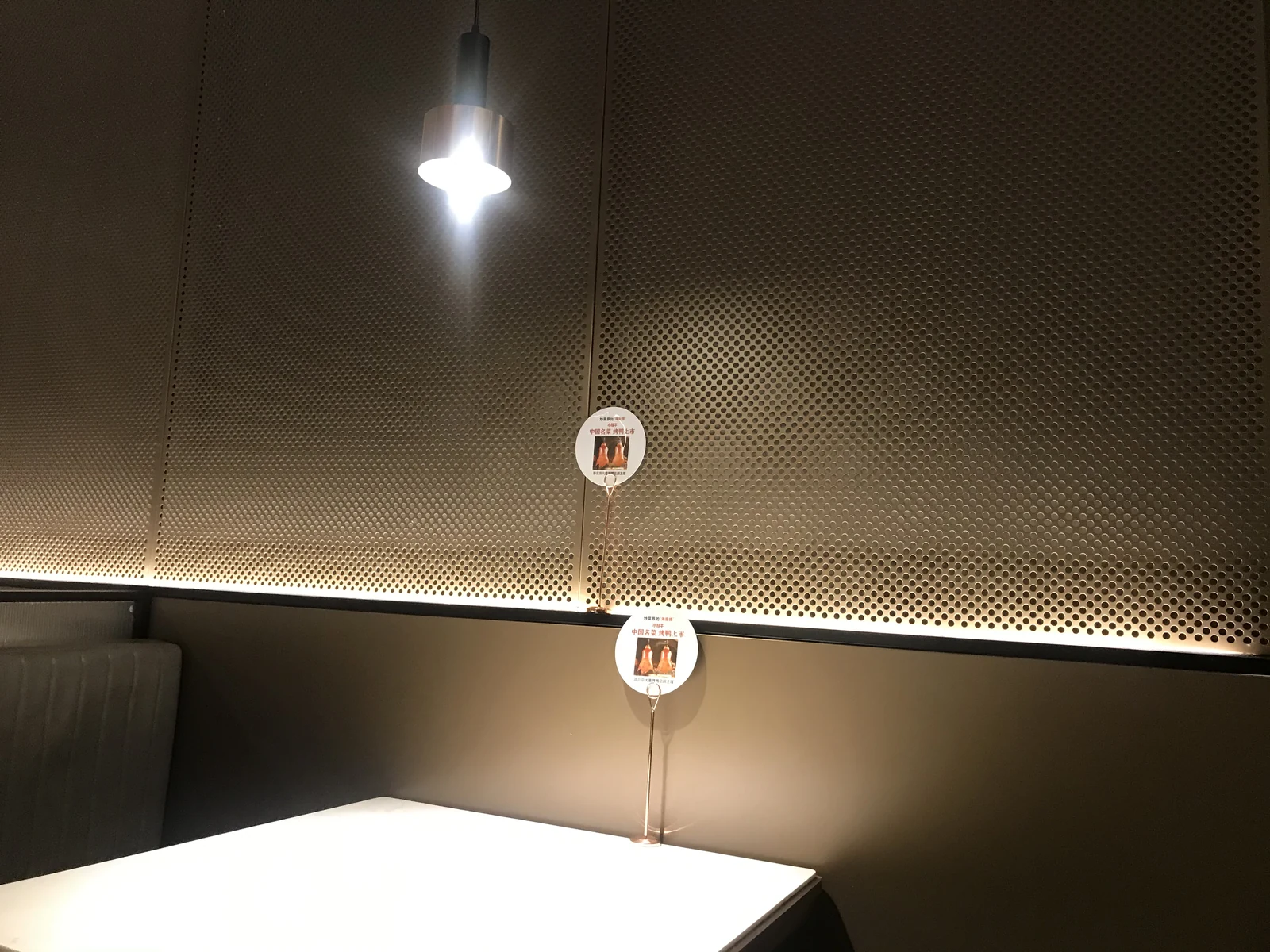 Perforated metal feature wall beside pendant lighting and a dining table