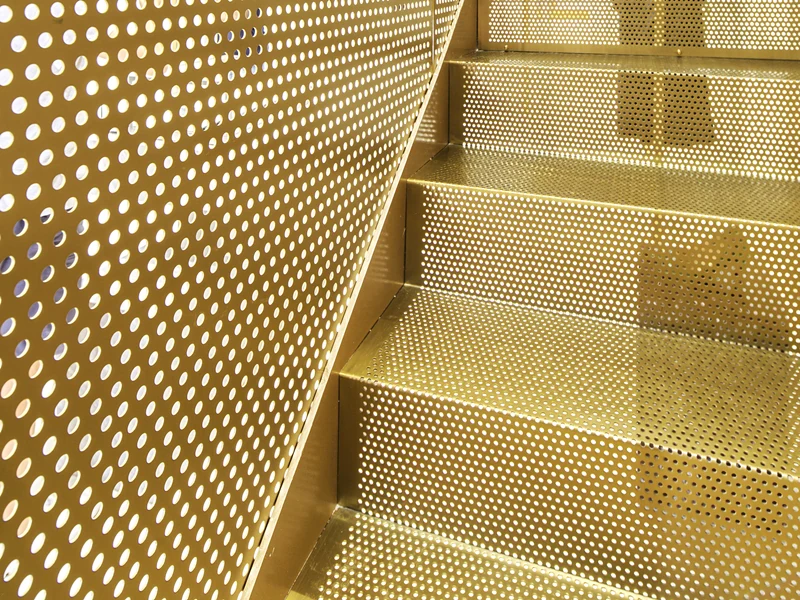 Round hole perforated metal panels enclosing an interior staircase