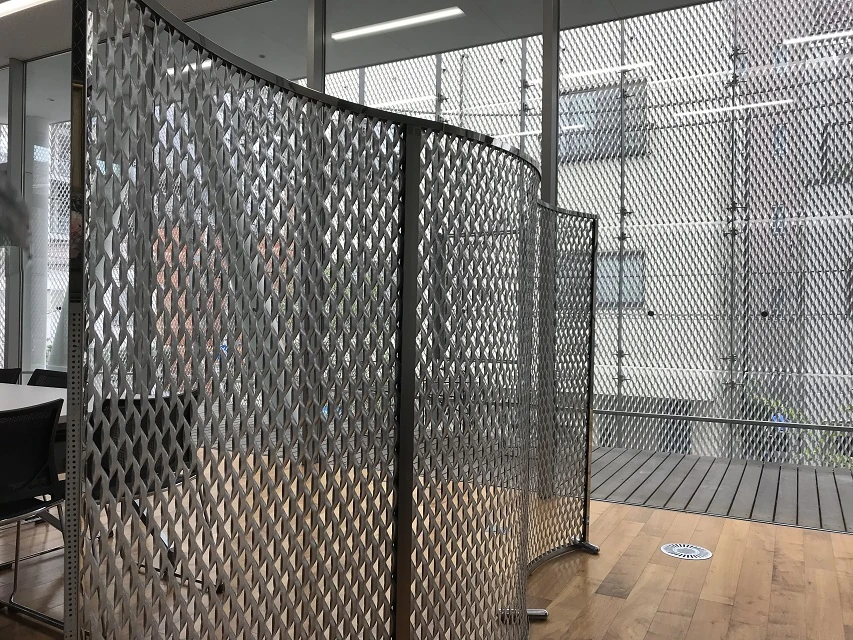 Expanded metal partition panels within dark frames in an interior space; application illustration