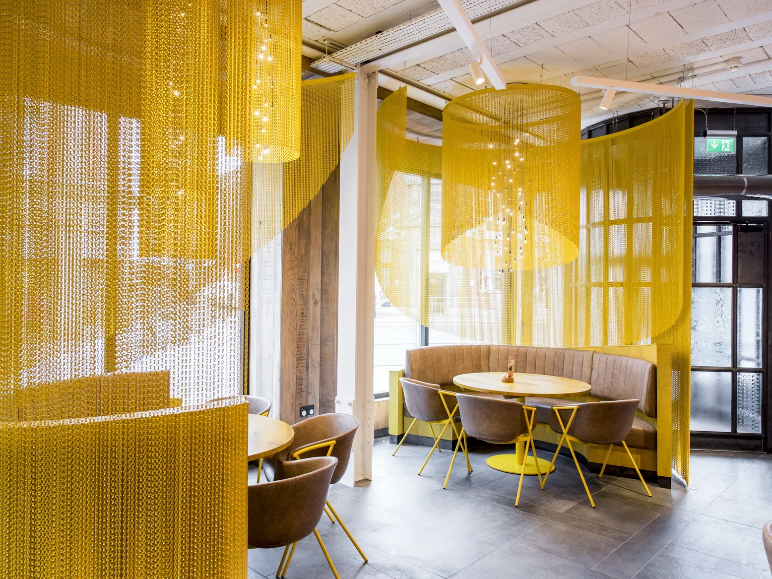 Yellow chain curtains dividing restaurant seating around dining tables