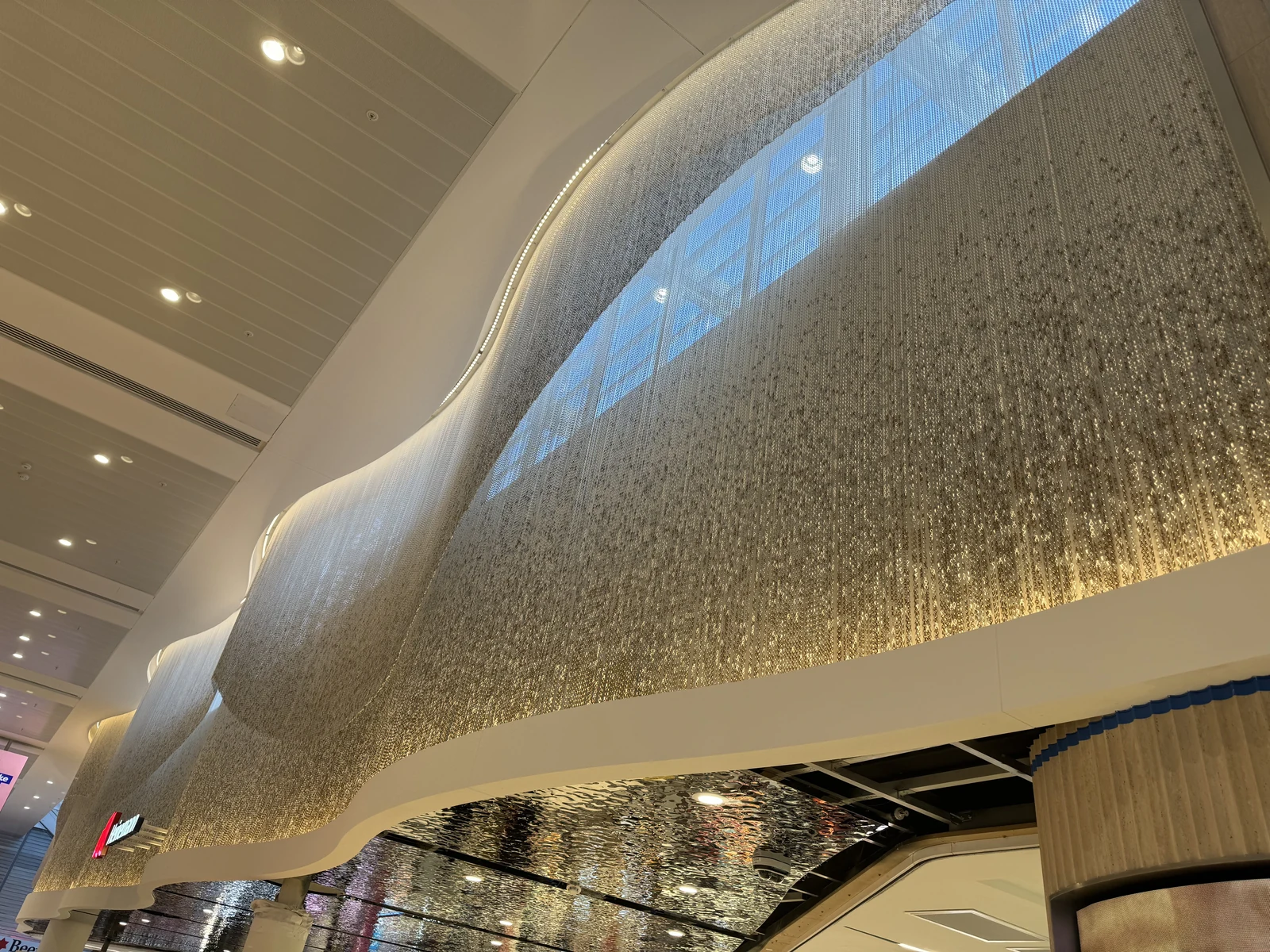 Suspended metal chain curtain forming an undulating interior feature beneath the ceiling