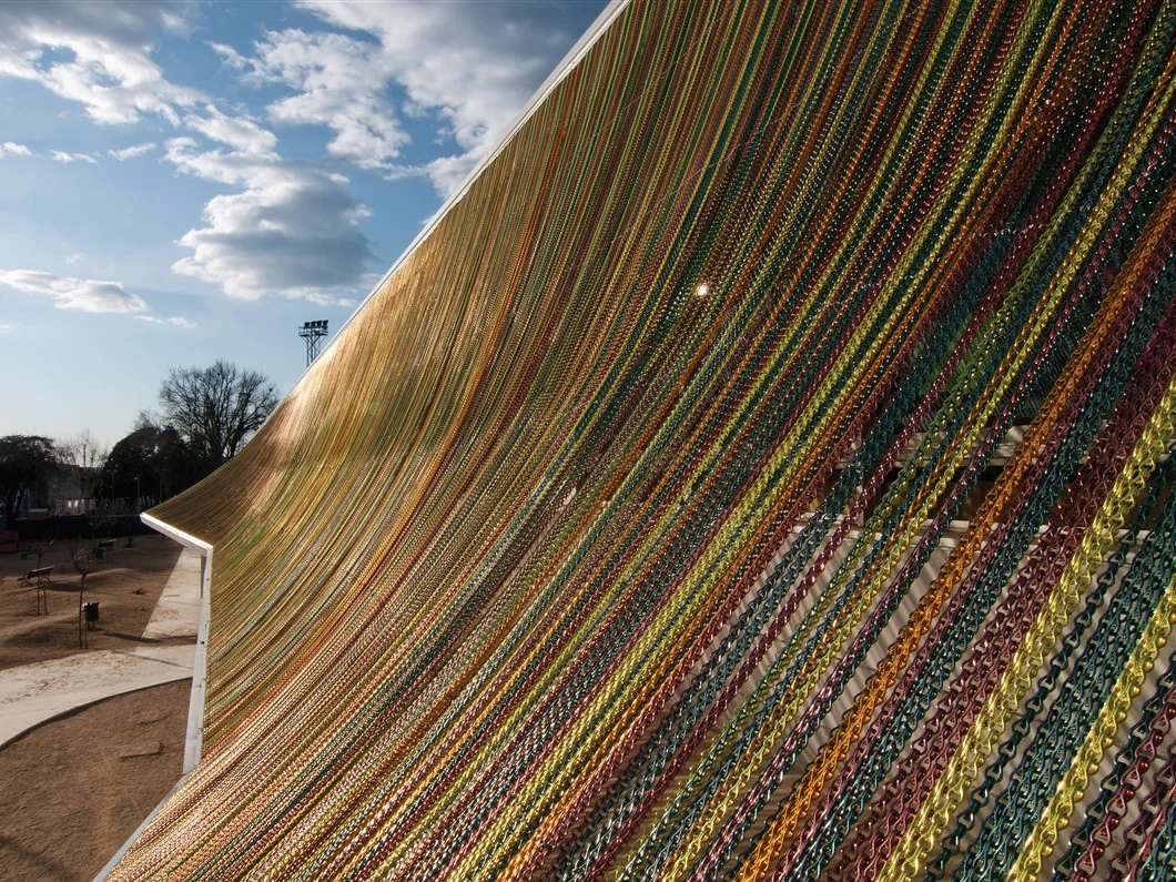 Multicolored chains draped across a curved outdoor installation