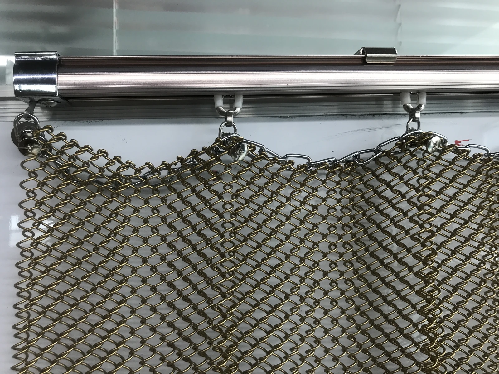 Metal coil drapery hanging beneath a horizontal top rail