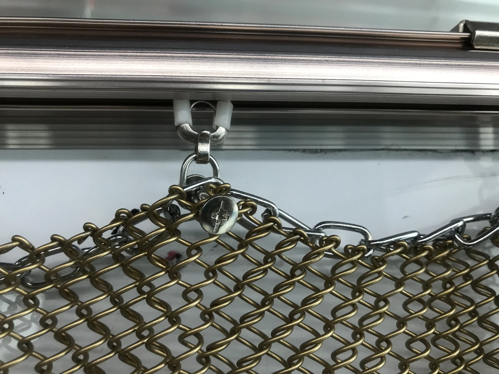 Metal coil drapery connected to a carrier beneath a horizontal track